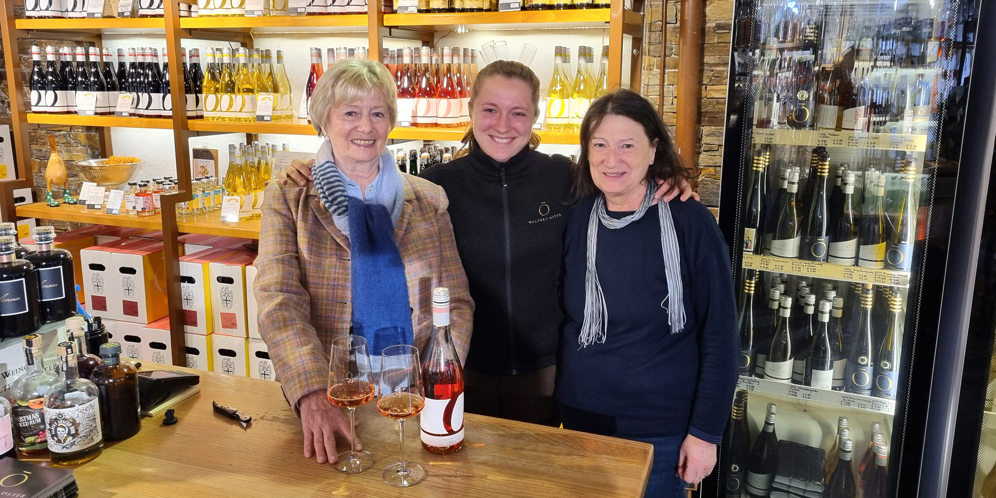 Isabelle Oster vom Weingut Oster mit ihren Kolleginnen Petra Wuttke und Hermine Hagen vor dem Weinregal